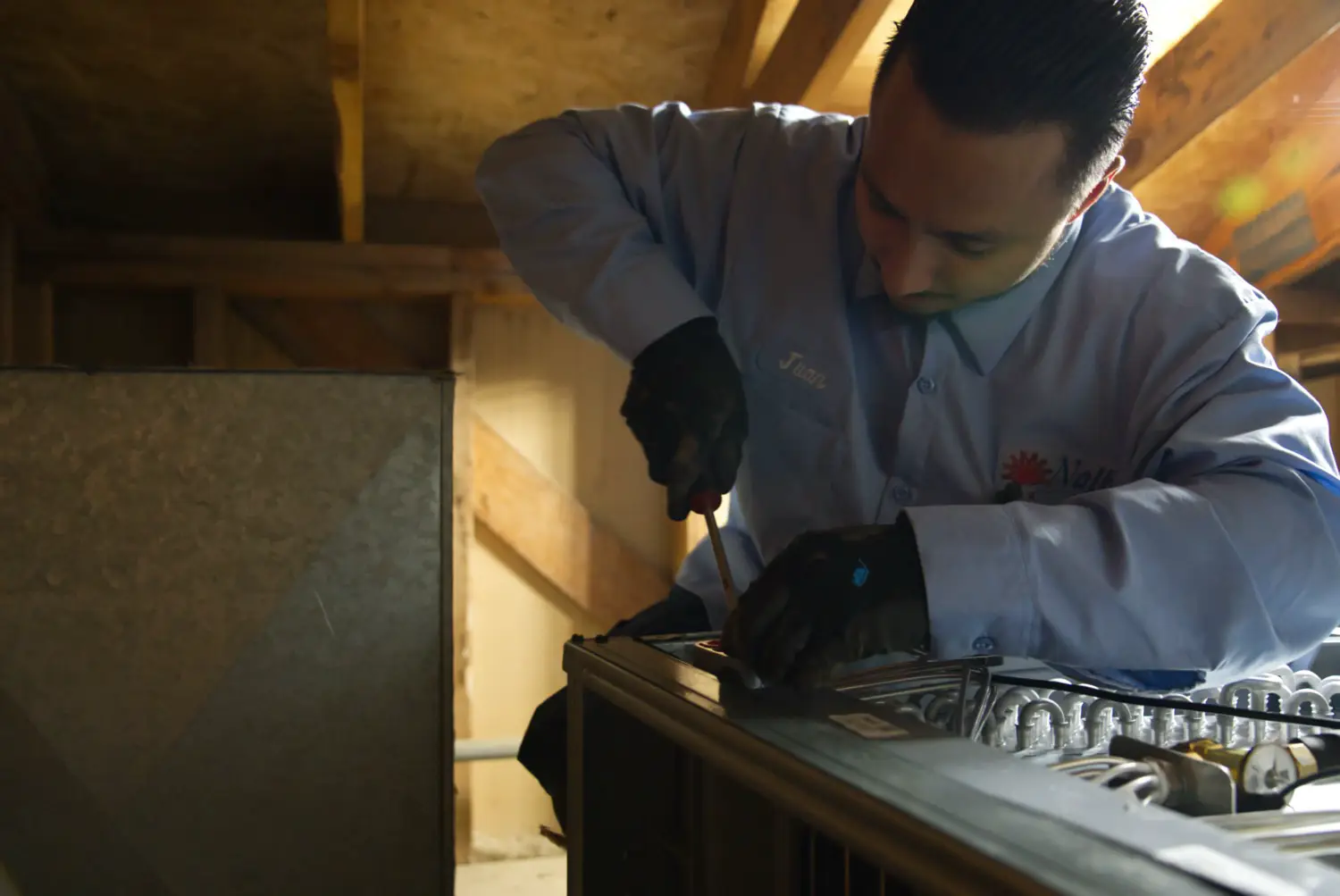 Nalk technician working on HVAC equipment in an attic