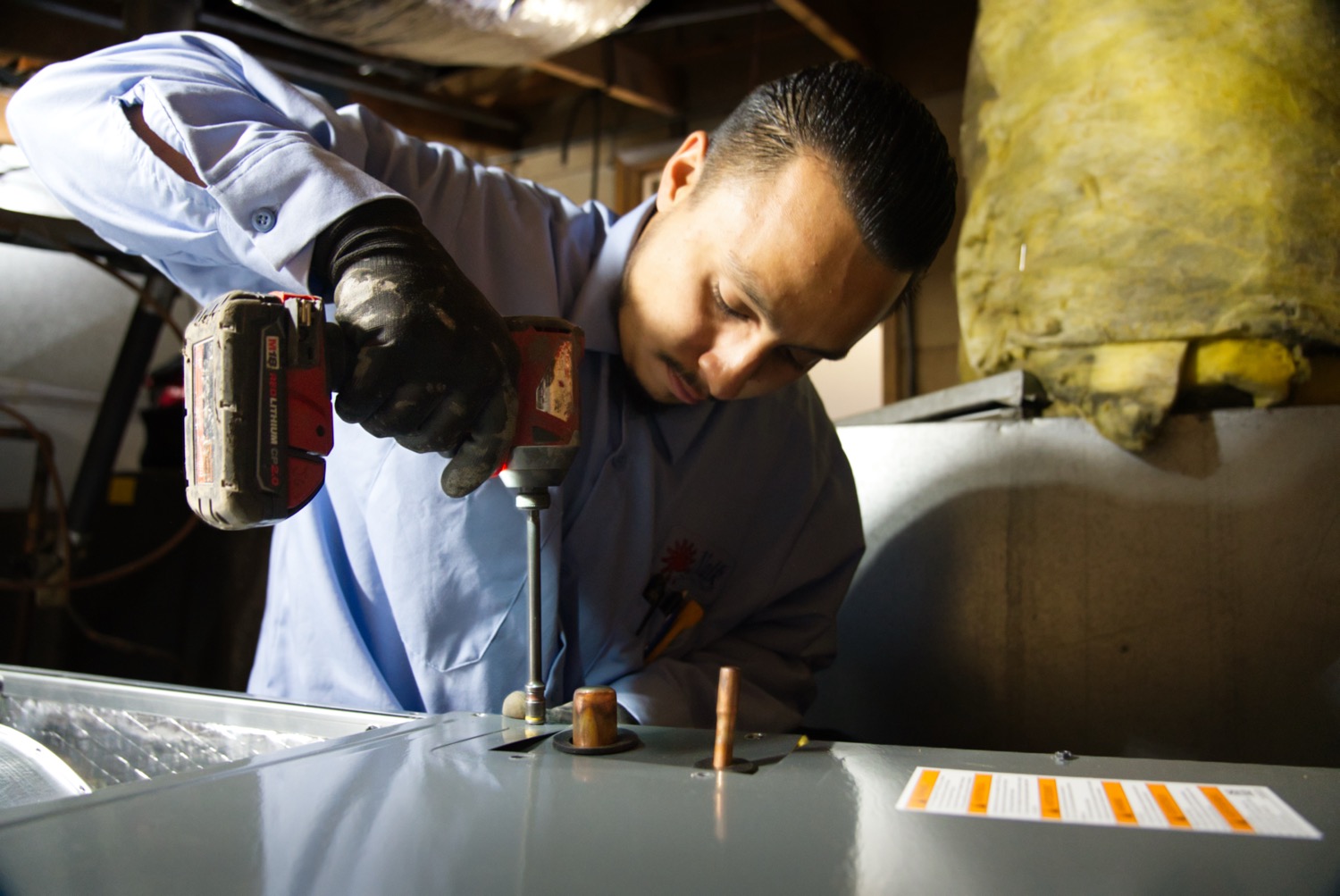 Technician inspecting an aging HVAC system in a Fresno home to determine if replacement is needed